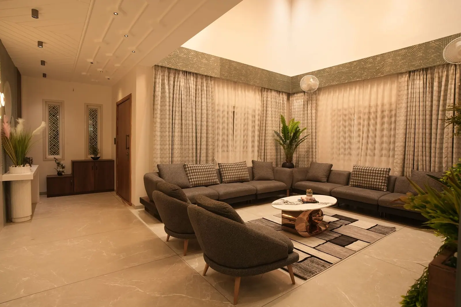 Living room — a large sectional sofa framed by sheer drapes and a stone floor.