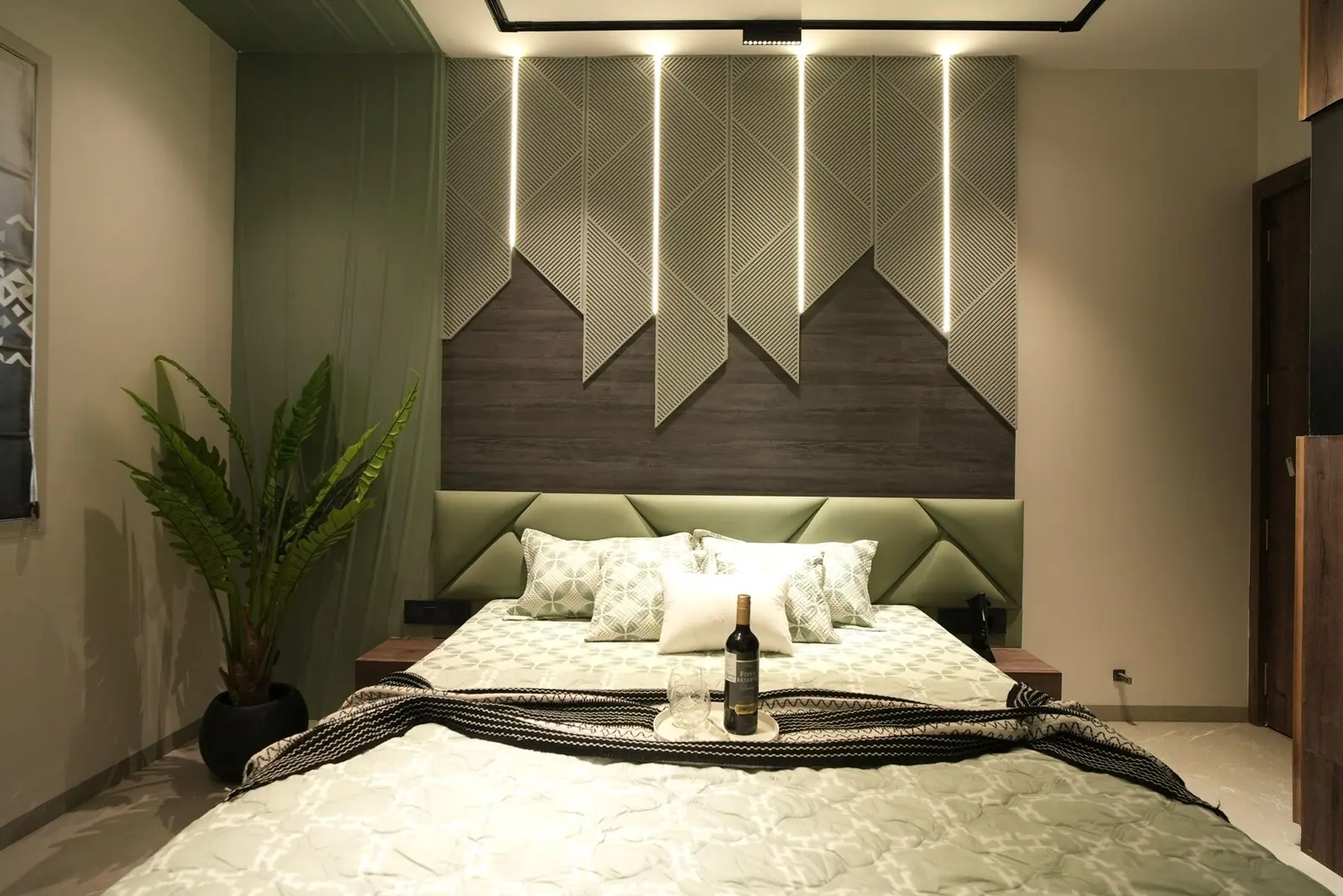 Bedroom — a geometric timber headboard set against a deep green wall with linear lighting.