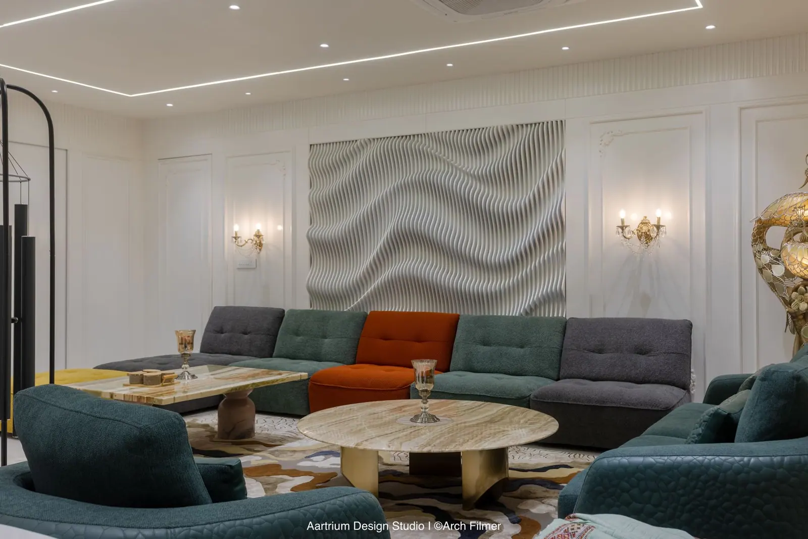 Living room — a sculpted wave art panel above a modular sofa with round stone tables.