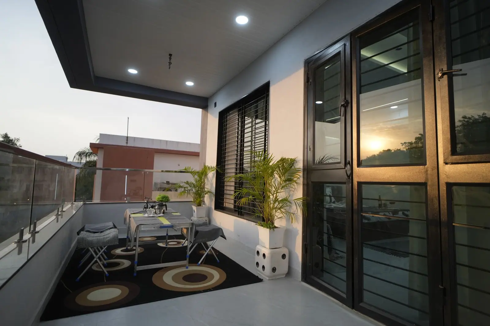 Balcony — a shaded sit-out with café seating beside full-height glazed doors.