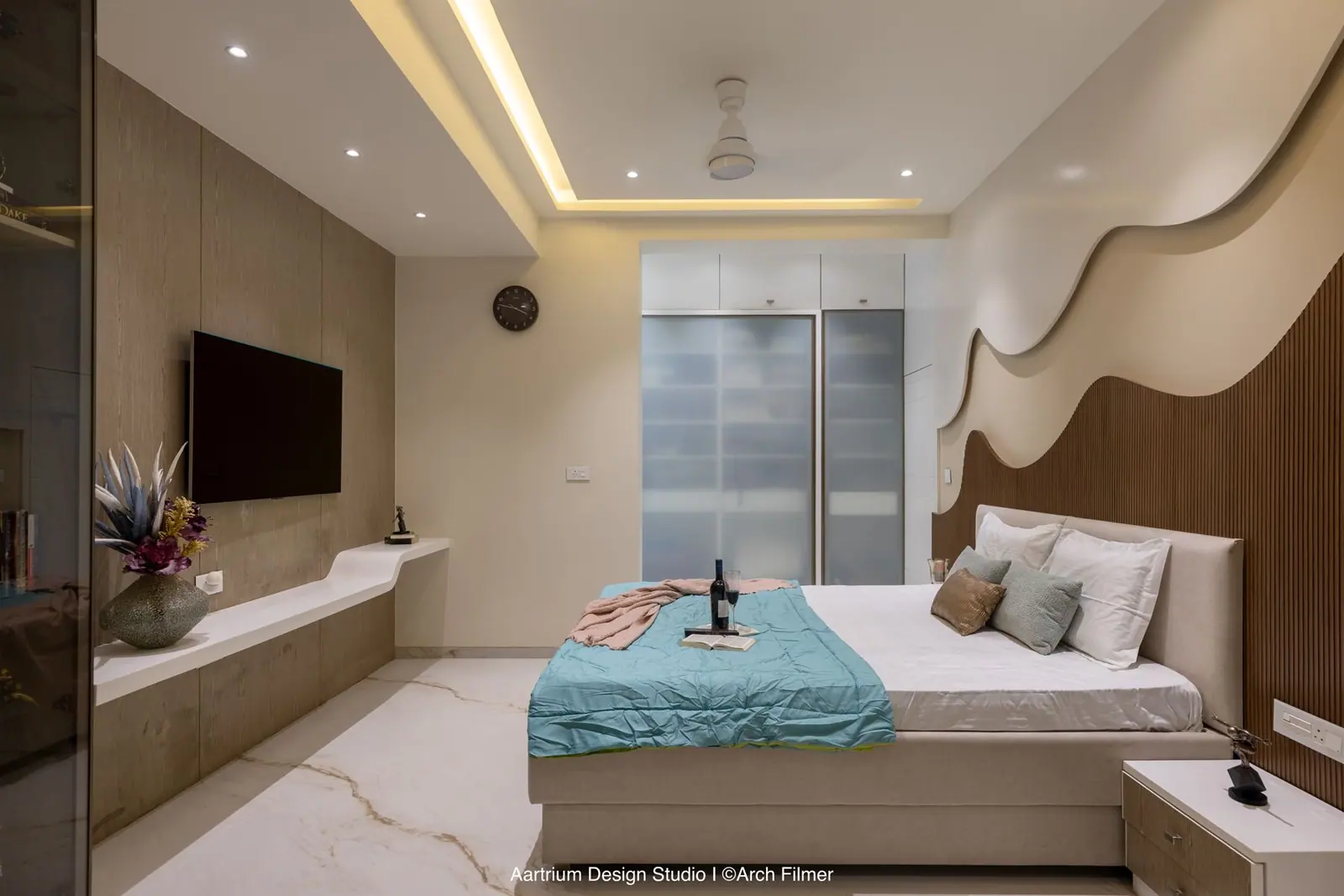 Bedroom — a timber wave-panel wall facing the bed, lit by a cove-lit curved ceiling.