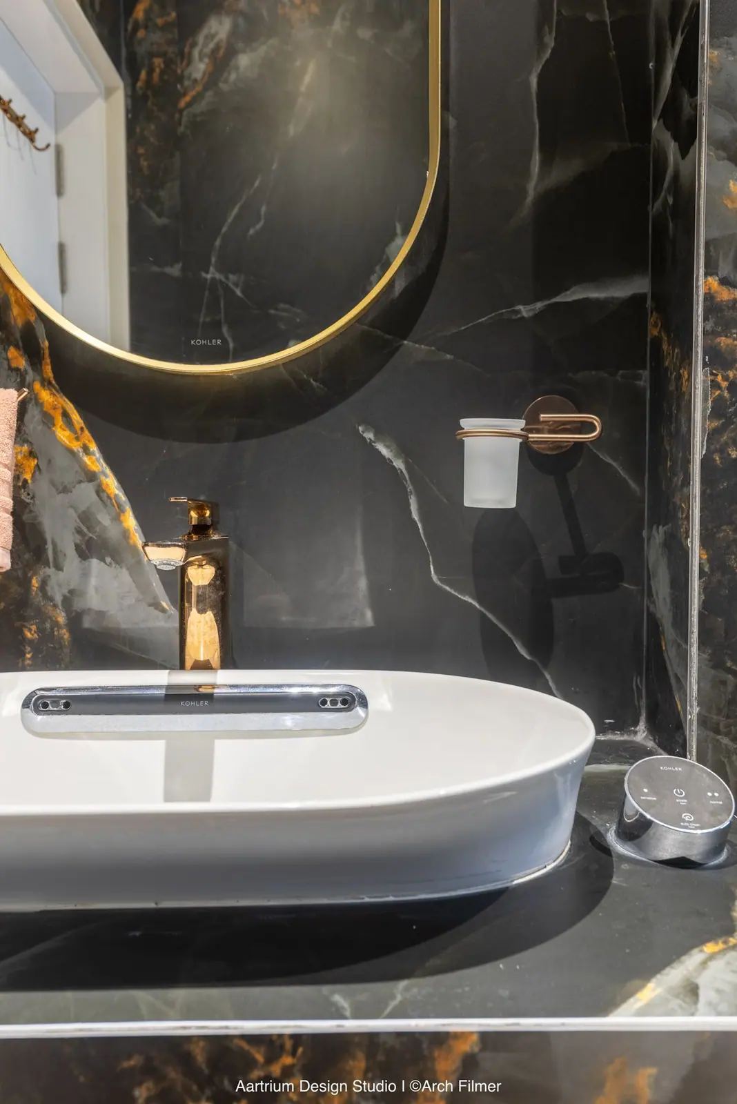 Washroom — a black-and-gold marble vanity with a backlit round mirror.
