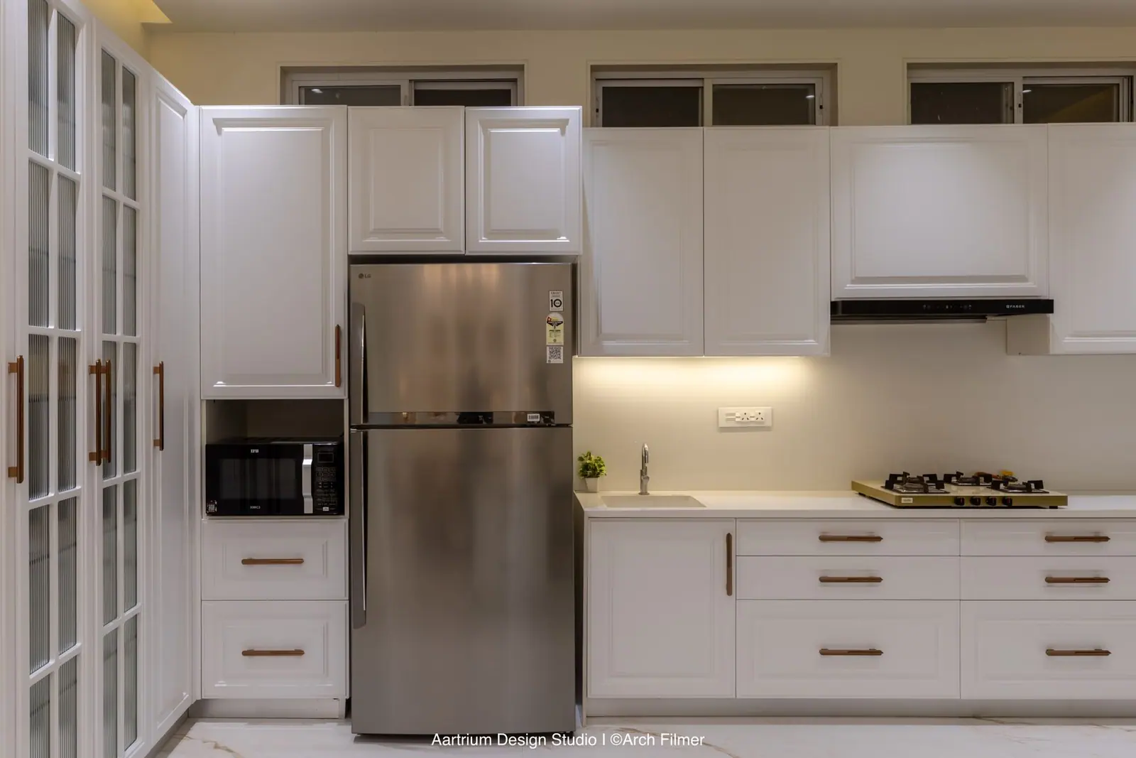 Kitchen — classic white shaker shutters with under-cabinet lighting and glazed tall units.