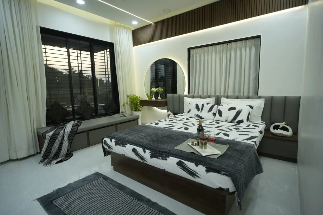 Bedroom — printed monochrome bedding against a fluted headboard wall with a corner window seat.