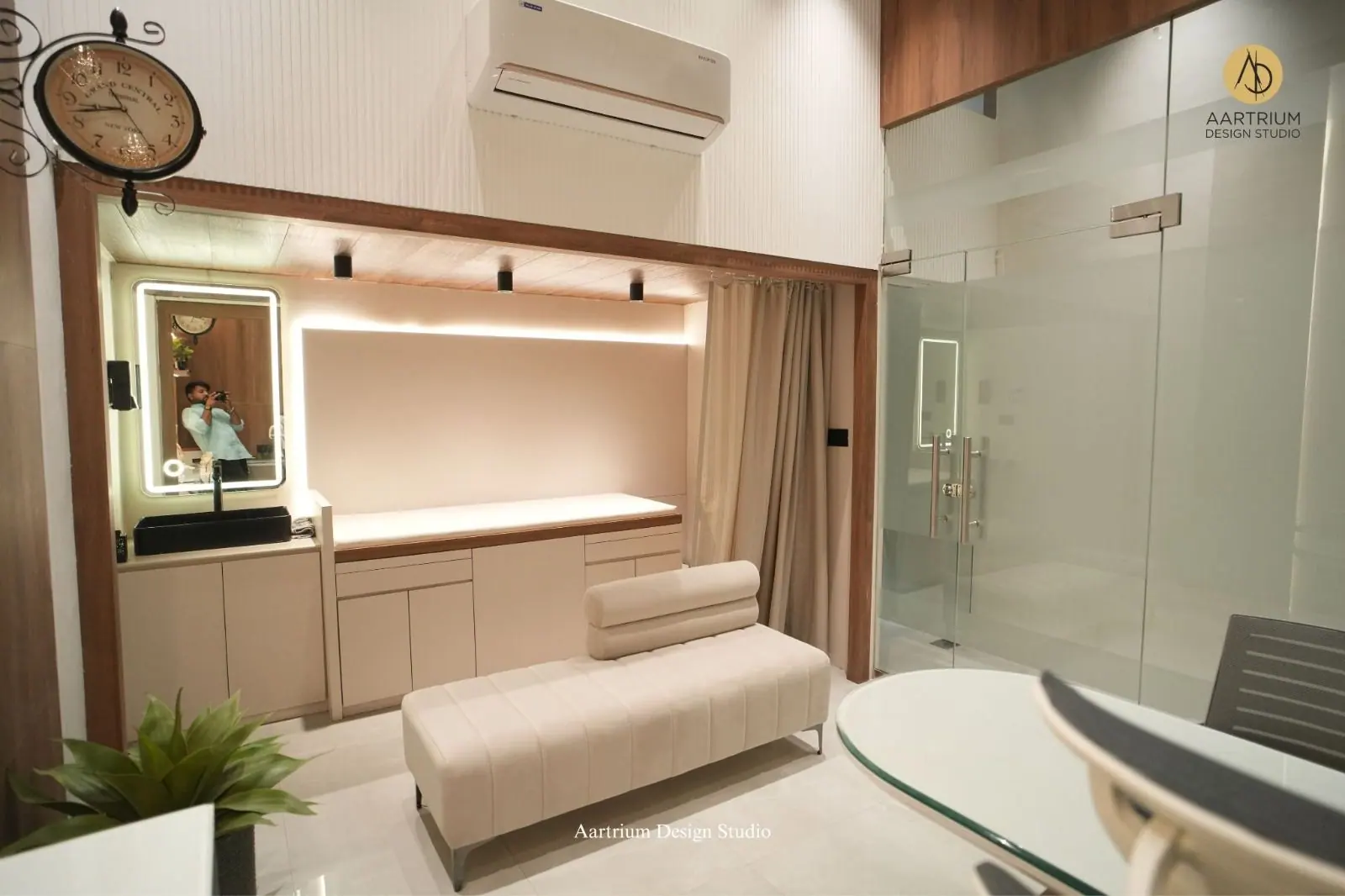 Treatment room — a backlit mirror wall with a long bench and a glazed cabin beyond.