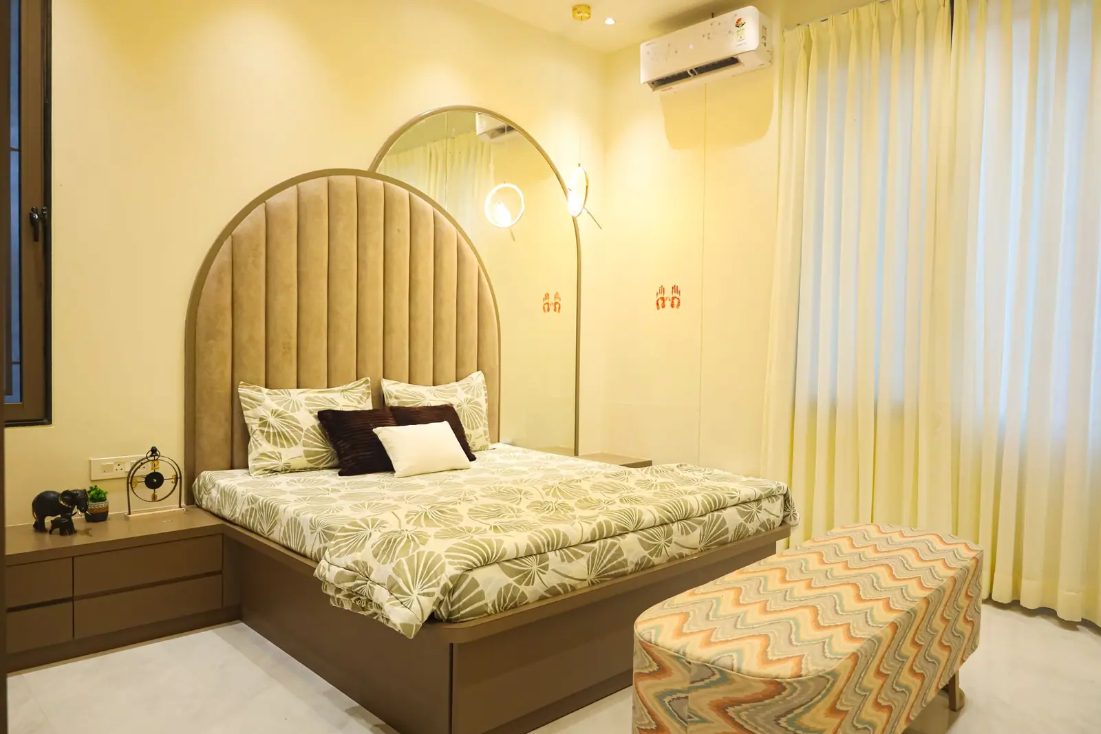 Bedroom — a tall arched upholstered headboard with a bedside pendant and window seat.