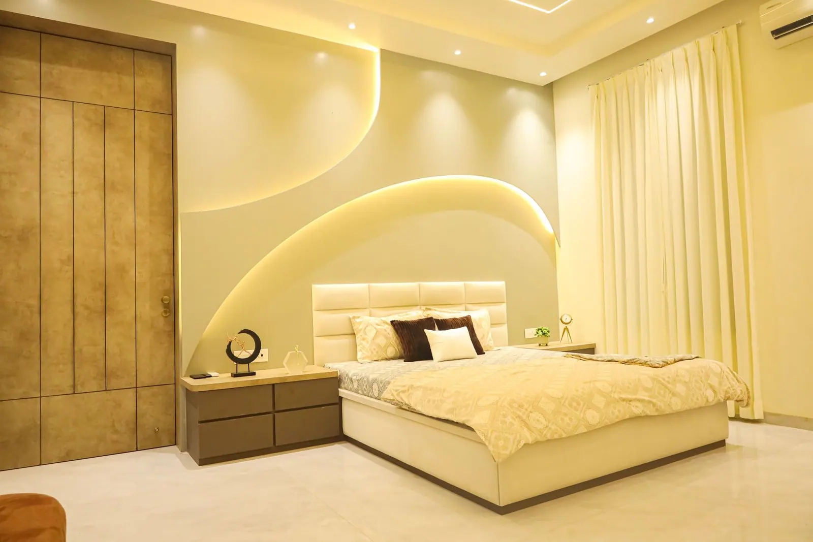 Bedroom — an arched, cove-lit headboard wall in cream with a timber entry door.